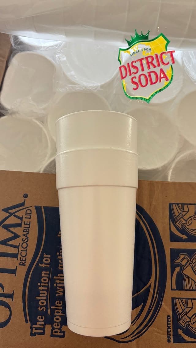 Double gobelet blanc collector District Soda posé sur un carton, accessoire de la marque
